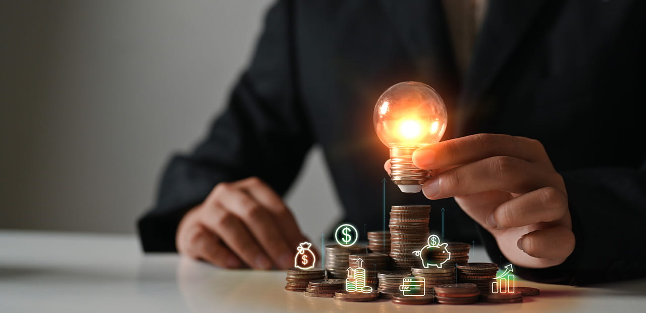 Businesswoman hand holding glowing lightbulb on coin stacking